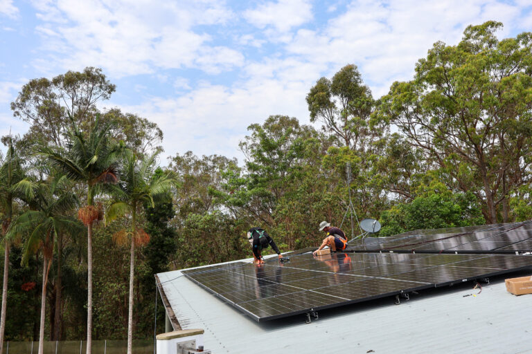 Meridien Energy team, located on the Gold Coast. The solar installers are positioning solar panels onto the roof of a Nerang Queensland Home. They have installed 60x Astronergy N7s 440W Bifacial Solar Panels. The home is surrounded by luscious gum trees.
