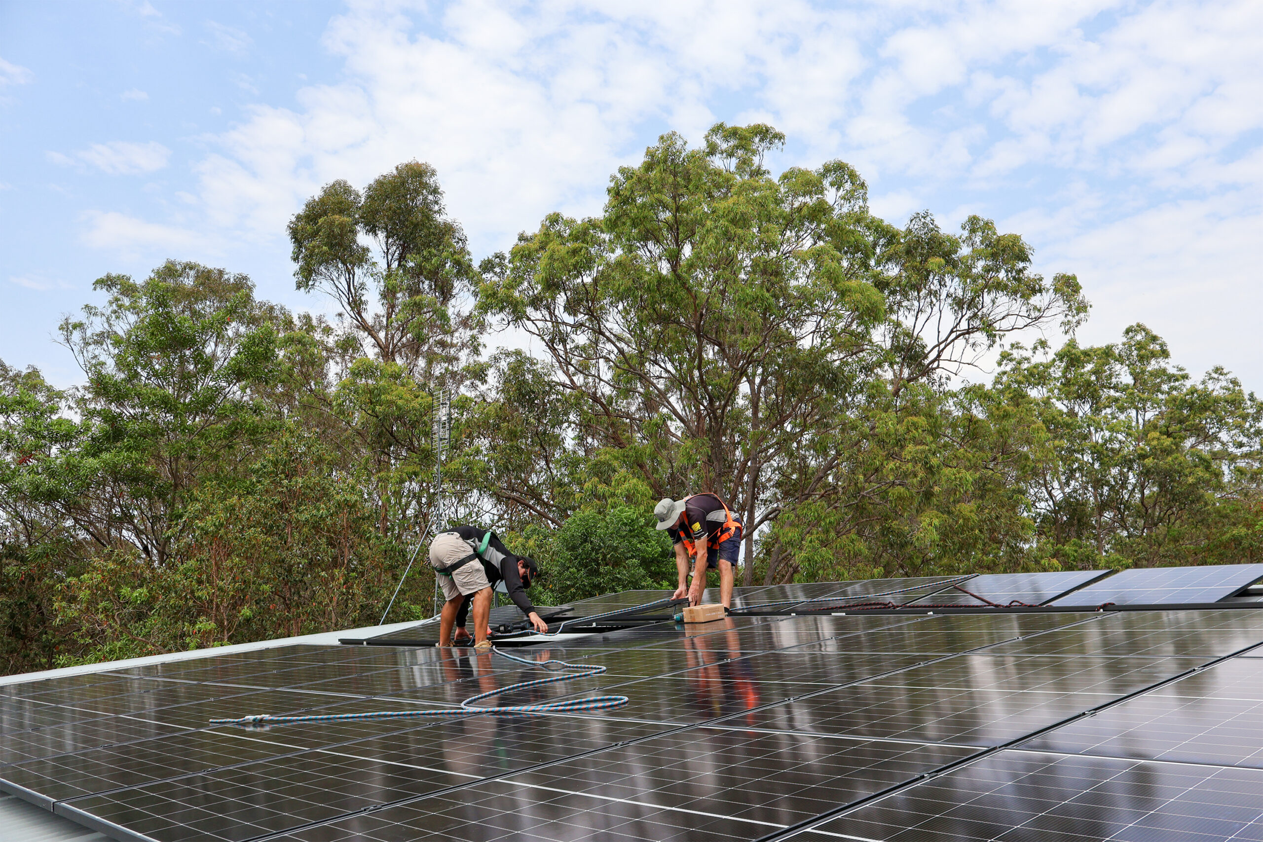 Meridien Energy team, located on the Gold Coast. The solar installers are positioning solar panels onto the roof of a Nerang Queensland Home. They have installed 60x Astronergy N7s 440W Bifacial Solar Panels. The home is surrounded by luscious gum trees.