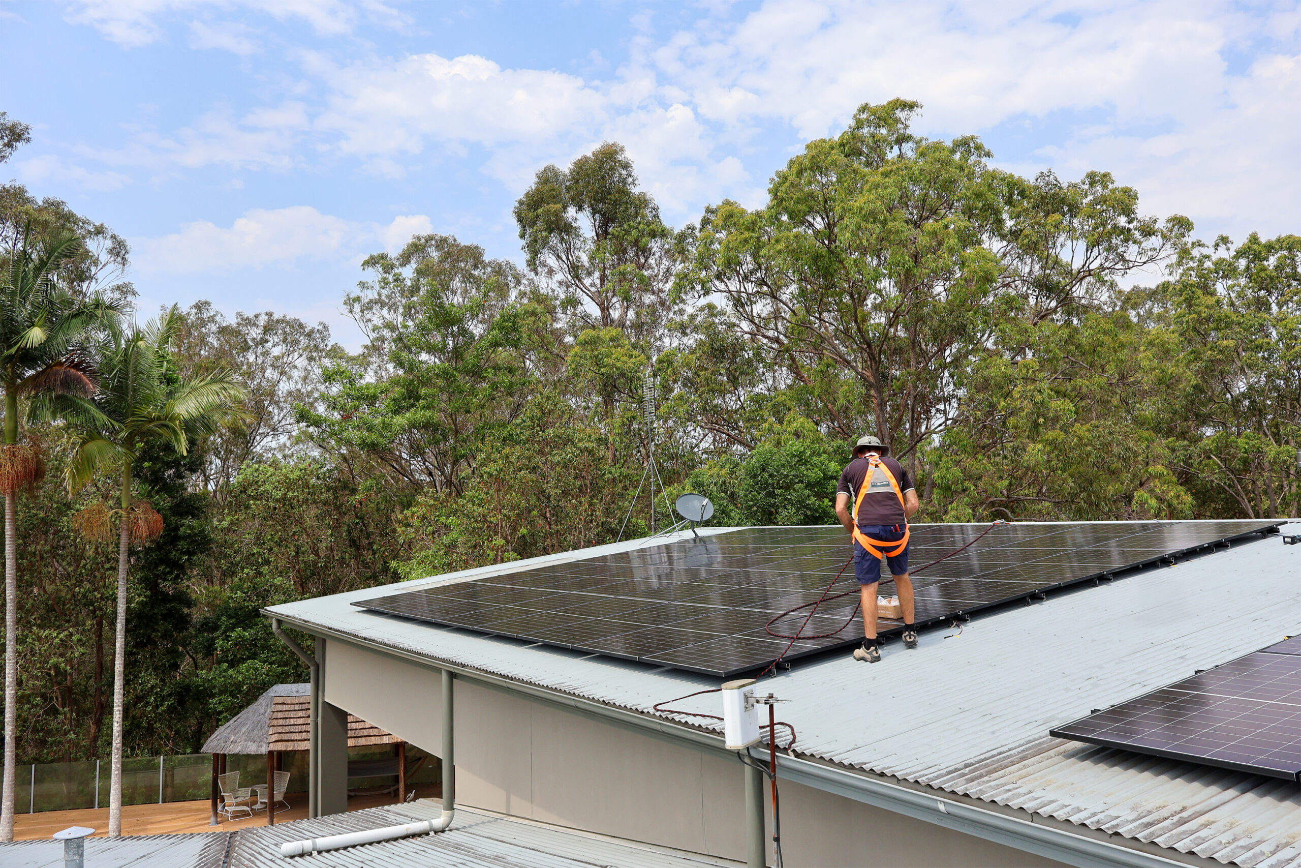 Meridien Energy team, located on the Gold Coast. The solar installer is positioning solar panels onto the roof of a Nerang Queensland Home. They have installed 60x Astronergy N7s 440W Bifacial Solar Panels. The home is surrounded by luscious gum trees.